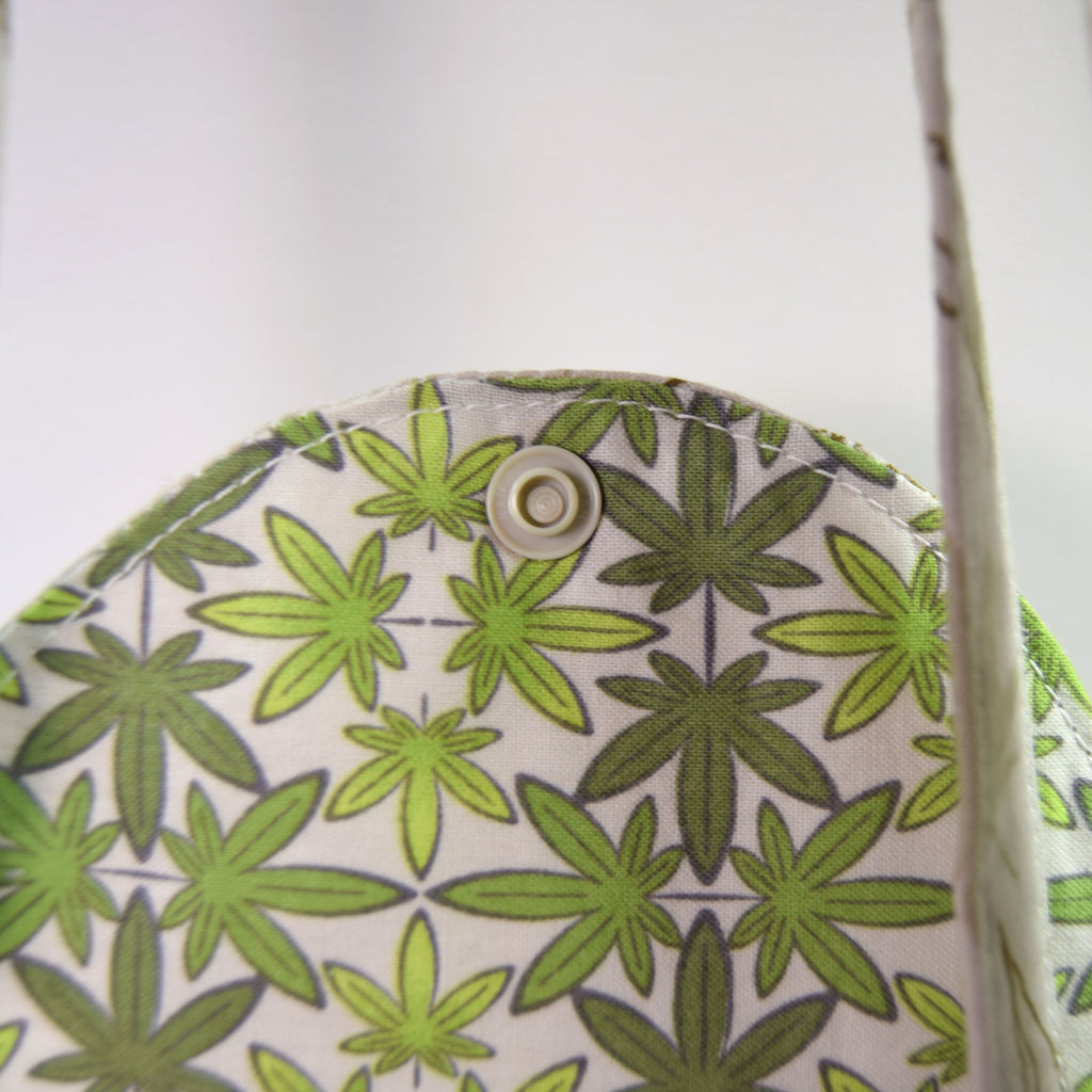 Fabric with green leaf pattern and button on a white background